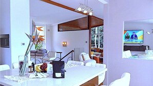 A modern living room with a white sofa set, a dining area with a white table, and a television mounted on the wall. - Grand Haven with Sea view! For Executives and Remote! Adults only! City Close! (Castlecrag)