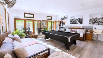 A spacious living room with a pool table, comfortable seating, and a large window with a view.