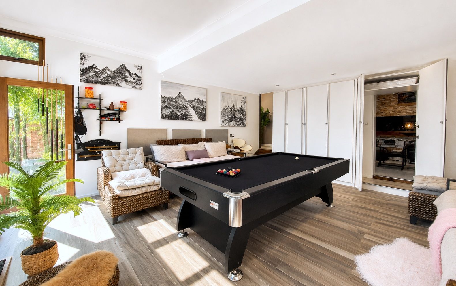 A modern living room with a pool table, comfortable seating, and artwork on the walls.