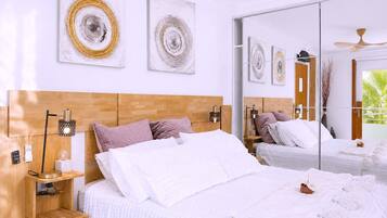 A modern bedroom with a large bed, bedside tables, wall art, and a sliding glass door leading to a balcony.