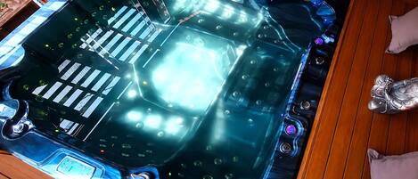 Et spabad med kontrolpanel, omgivet af trægulv.