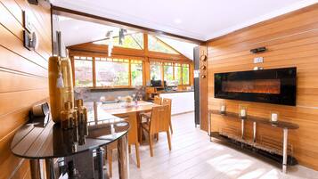 A modern kitchen with a flat-screen TV, wooden cabinetry, and a dining area with a round table and chairs.