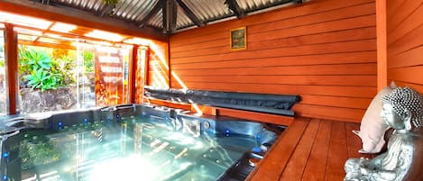 A hot tub area with a wooden bench and a Buddha statue.