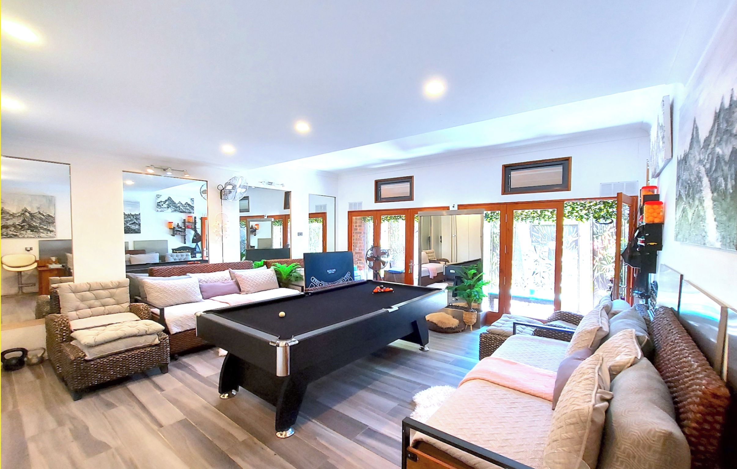 Un salon spacieux avec une table de billard, des sièges confortables et une vue sur l’extérieur.