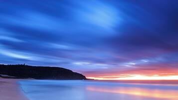 A beach with a calm sea and a sunset sky.
