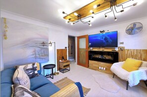 A modern living room with a large painting, a flat-screen TV, and a cozy sofa.