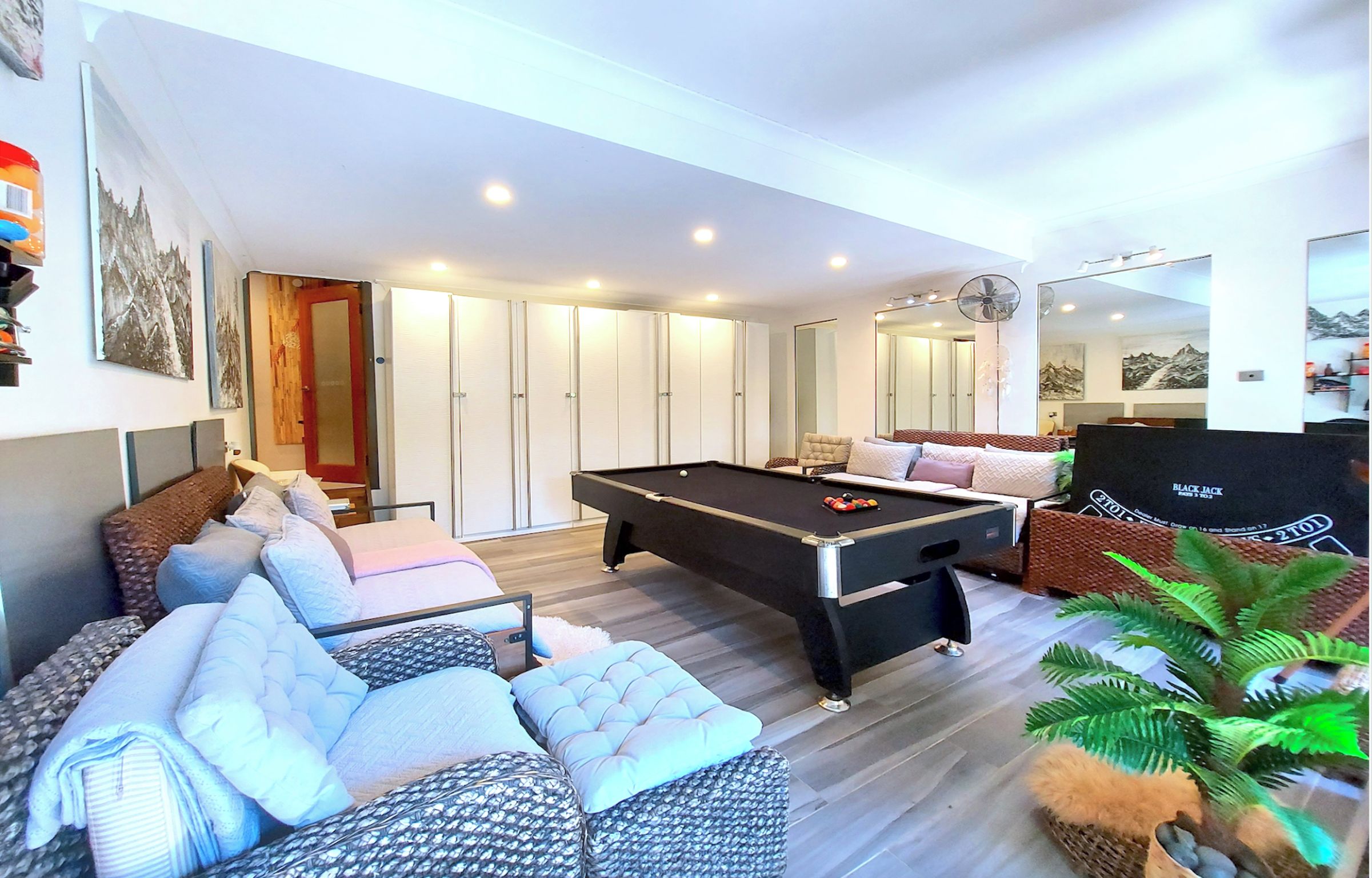 A modern living room with a pool table, comfortable seating, and a large mirror.