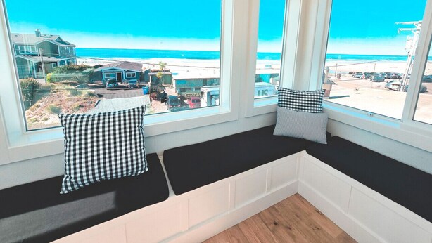 Ein Zimmer mit einer großen Fensterbank mit Blick auf einen Strand.