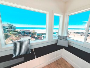 Una habitación con un amplio asiento junto a la ventana con vistas a la playa.