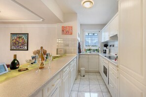 A kitchen with white cabinets, a countertop, a sink, and a window. - Apartment 'Linas Lieblingsplatz' with Balcony & Piano (Uhldingen-Mühlhofen)
