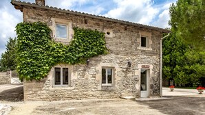Un bâtiment en pierre dont la façade est partiellement recouverte de lierre, avec une petite porte et une enseigne indiquant « Le Bercail ».