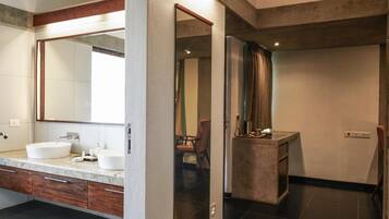 A modern bathroom with a large mirror, two sinks, and a vanity with drawers.