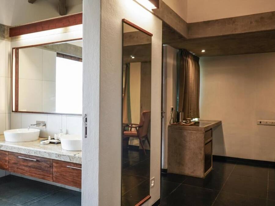 A modern bathroom with a large mirror, two sinks, and a vanity with drawers.