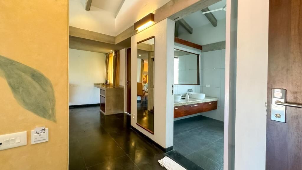 A hotel hallway with a modern design, a bathroom with a large mirror, and a door leading to another room.