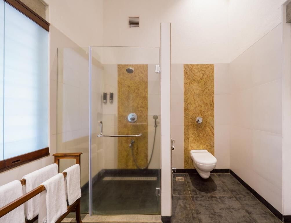 Une salle de bain moderne avec une douche à parois de verre, des toilettes et un banc avec des serviettes.
