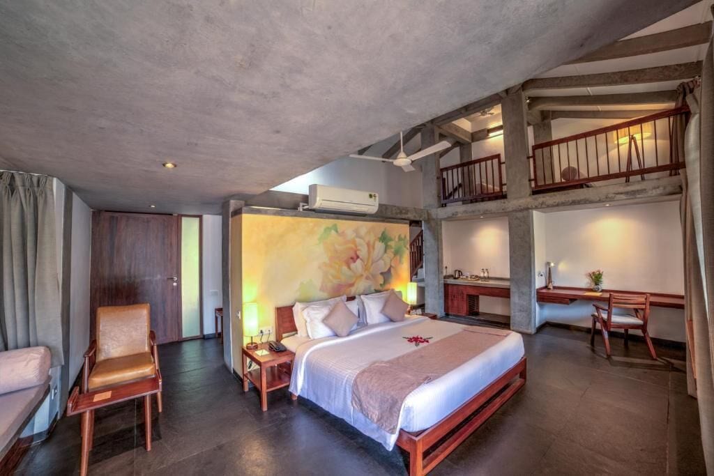 Een slaapkamer met een bed, bureau, stoel en een trap.