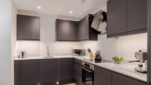 Eine moderne Küche mit dunklen Schränken, einer Mikrowelle, einem Backofen und einem Spülbecken.