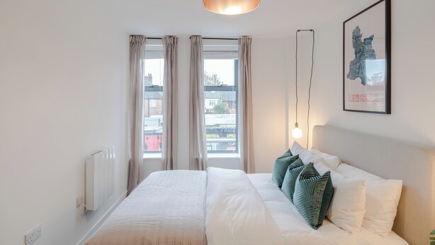 Ein modernes Schlafzimmer mit einem großen Bett, Blick auf die Stadt und einer gerahmten Karte an der Wand.