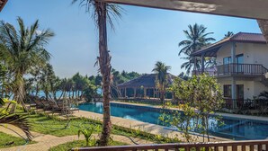 A resort with a swimming pool, palm trees, and a building with a balcony. - Arinna Beach Resort (Tangalle)