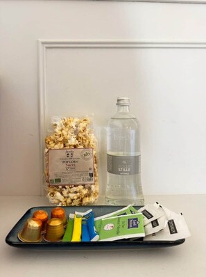 A tray with popcorn, a bottle of water, and tea packets. - Lily (Cannes)