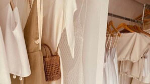 Un perchero con varios vestidos y un bolso tejido.