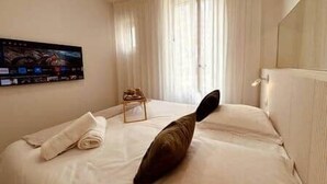 Habitación de hotel con cama, una silla, un radiador y un cuadro en la pared.