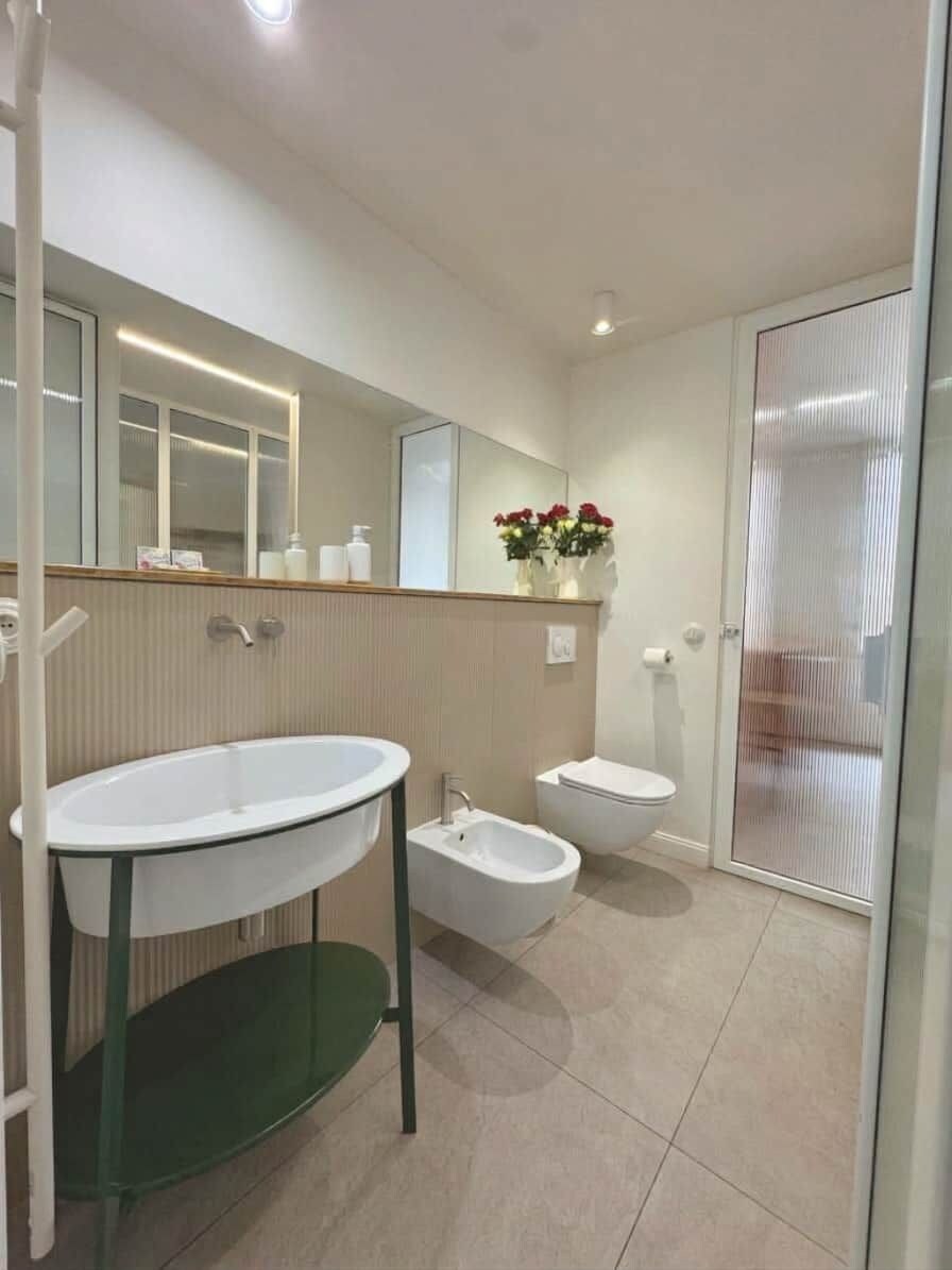 A modern bathroom with a large vanity, a bidet, and a glass shower enclosure.
