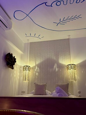 Ein Schlafzimmer mit einem Bett, zwei Wandlampen und einem dekorativen Wandbild.