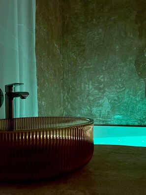 Ein Badezimmer mit einem runden, metallischen Waschbecken und einem wandmontierten Wasserhahn.