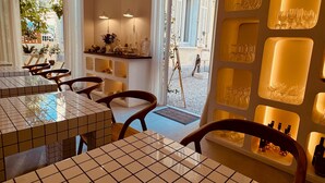 En restaurang med kakelbeklädda bord och stolar, en bardisk med en vas med blommor och utsikt över gatan utanför.