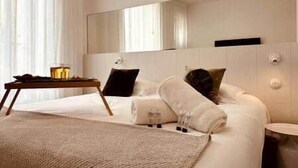 Een moderne hotelkamer met een groot bed, een nachtkastje met een lamp en een spiegel boven het bed.