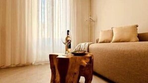 Een slaapkamer met een bed, een houten kruk en een raam met gordijnen.