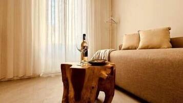 Une chambre à coucher avec un lit, un tabouret en bois et une fenêtre avec des rideaux.
