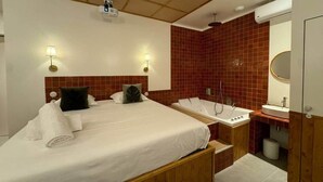 Et hotelværelse med seng, badeværelse med vask og spejl, samt loft med projektor.