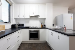 Eine moderne Küche mit weißen Schränken, einer schwarzen Arbeitsplatte, einem eingebauten Backofen, einer Mikrowelle und einem Spülbecken.