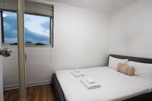 A bedroom with a bed, white walls, a window, and a door. - Cosy 2 BDR APT in heart of Fremantle with Parking (Fremantle)