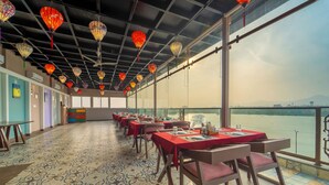 Ein Restaurant mit gedeckten Tischen, einem gemusterten Boden und Blick auf ein Gewässer.