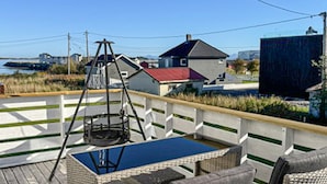 A deck with a swing set, a table, and a chair. - Awesome home in Harøya (Harøya)