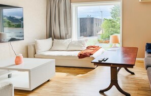 A modern living room with a sofa, a coffee table, a TV, and a window with a view of the outdoors.
