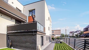 Ein modernes Wohngebäude mit flachem Dach, großen Fenstern und einem gepflasterten Weg.