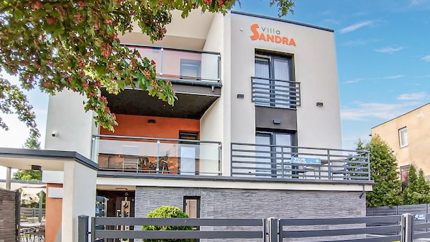 Ein modernes Hotel namens 'Villa Sandra' mit zweistöckiger Bauweise, einem Balkon und einem verschlossenen Eingang.