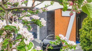 Ein modernes Gebäude mit schwarzer und orangefarbener Fassade, umgeben von blühenden Bäumen und einem ordentlich angelegten Garten.