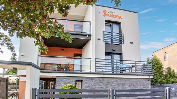 Un hôtel moderne à l’architecture contemporaine, avec deux étages, des balcons et une enseigne indiquant « Villa Sandra ».