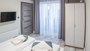 Une chambre d’hôtel avec deux lits, une armoire, une télévision et une fenêtre avec des rideaux.