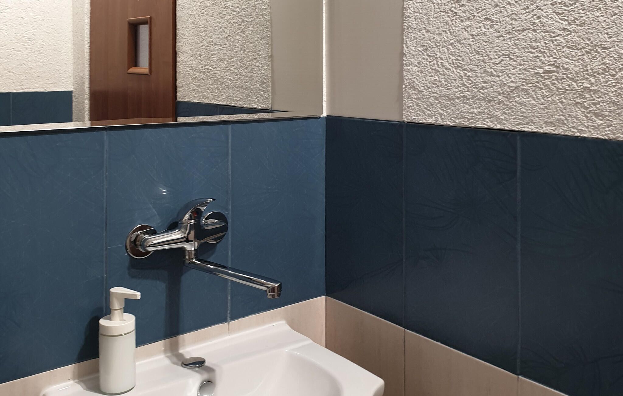 Ein Badezimmer mit einem weißen Waschbecken, einem Chrom-Wasserhahn und einer Seifenspender.