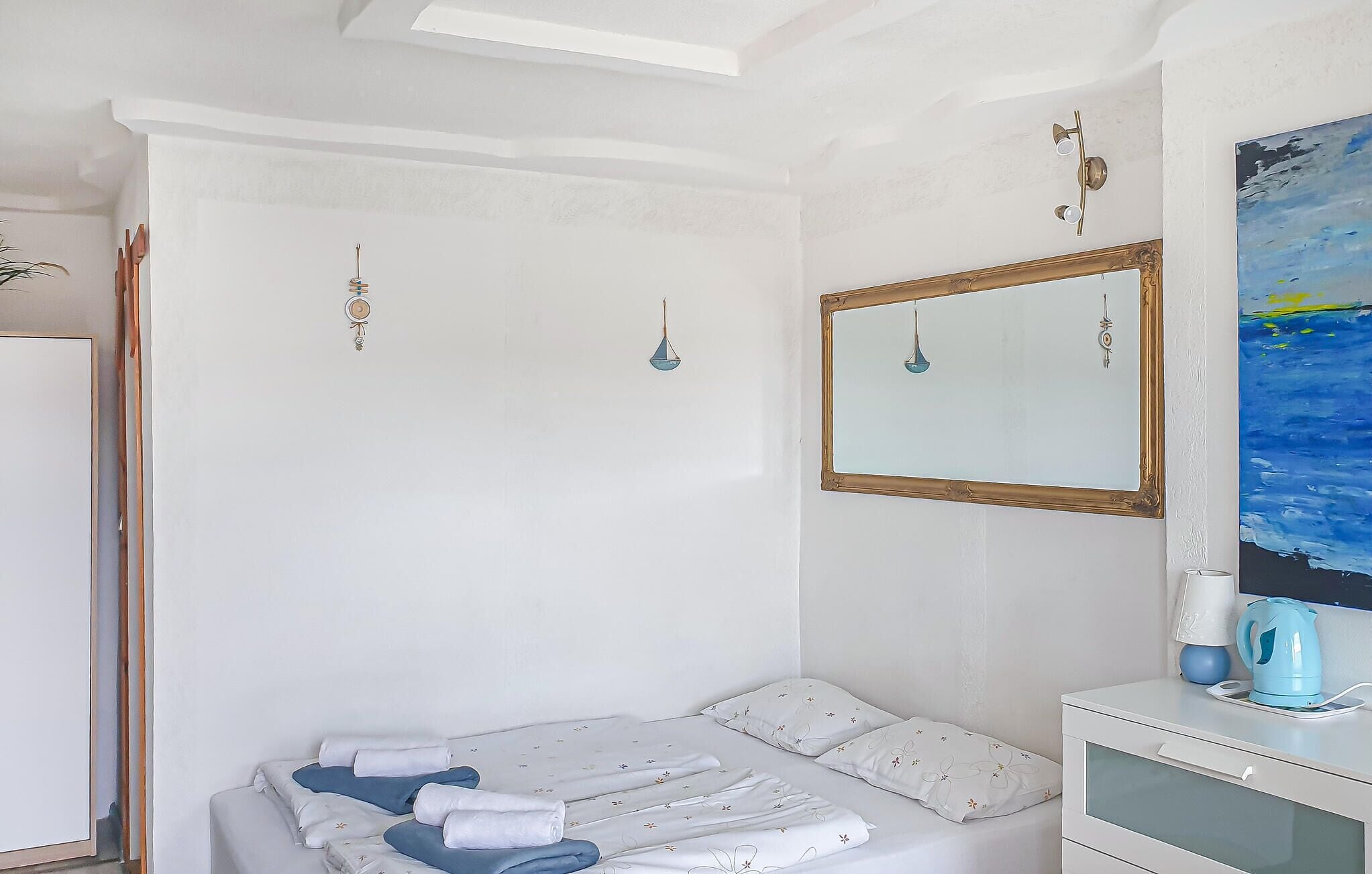 A bedroom with a bed, a dresser, a mirror, and a painting on the wall.