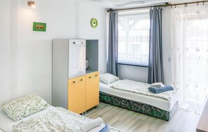 A compact bedroom with a bed, a wardrobe, a small table, and a window with curtains. - Lovely apartment in Leba with WiFi (Leba)