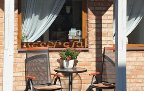 An outdoor seating area with two chairs and a table, a window with curtains, and a brick wall. - Lovely apartment in Leba with WiFi (Leba)