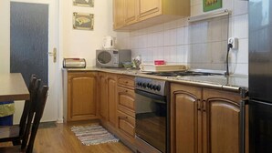 Cucina con mobili in legno, piano cottura, forno a microonde e frigorifero.