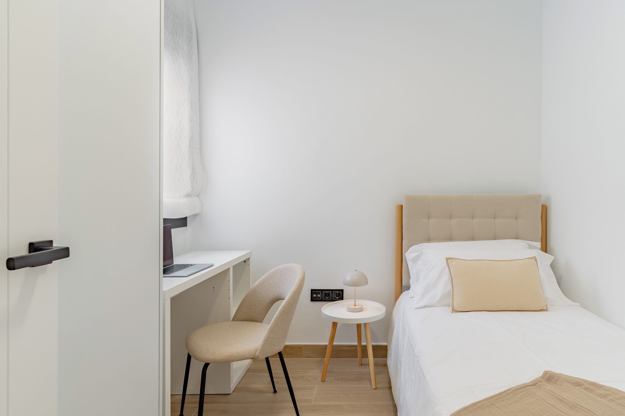 Une chambre à coucher comprenant un lit, un bureau, une chaise et une petite table avec une lampe.